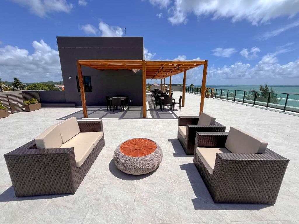 Rooftop do Kauai Beach Residence com sofás, pérgola e vista para o mar de Tamandaré