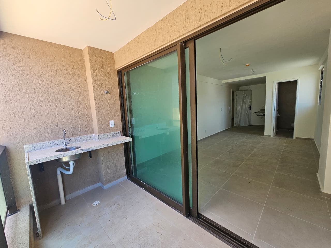 Varanda com bancada e porta de vidro de um flat do Kauai Beach Residence