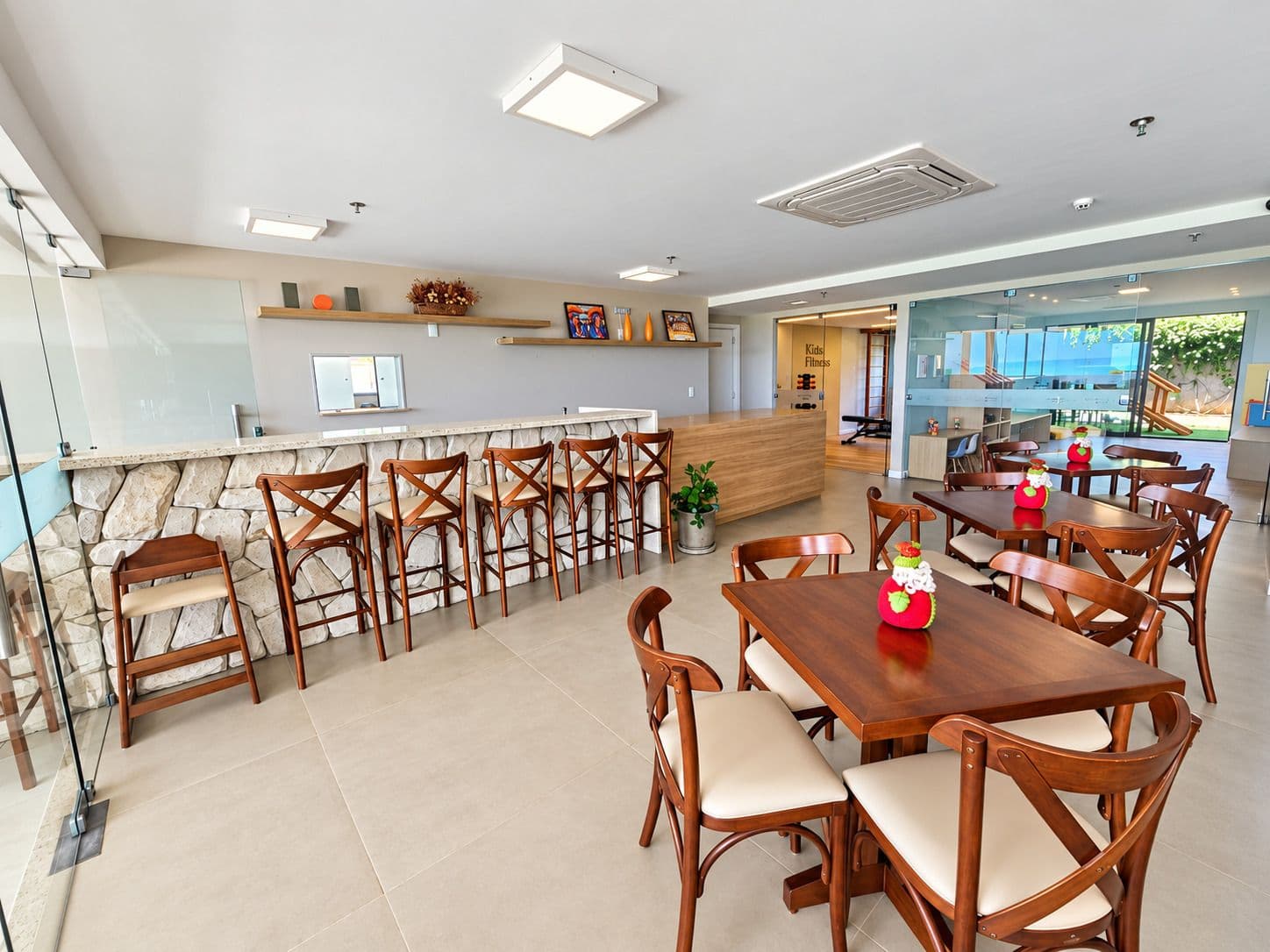 Coffee shop e bar de convivência do Kauai Beach Residence, com espaço fitness e sala kids ao fundo