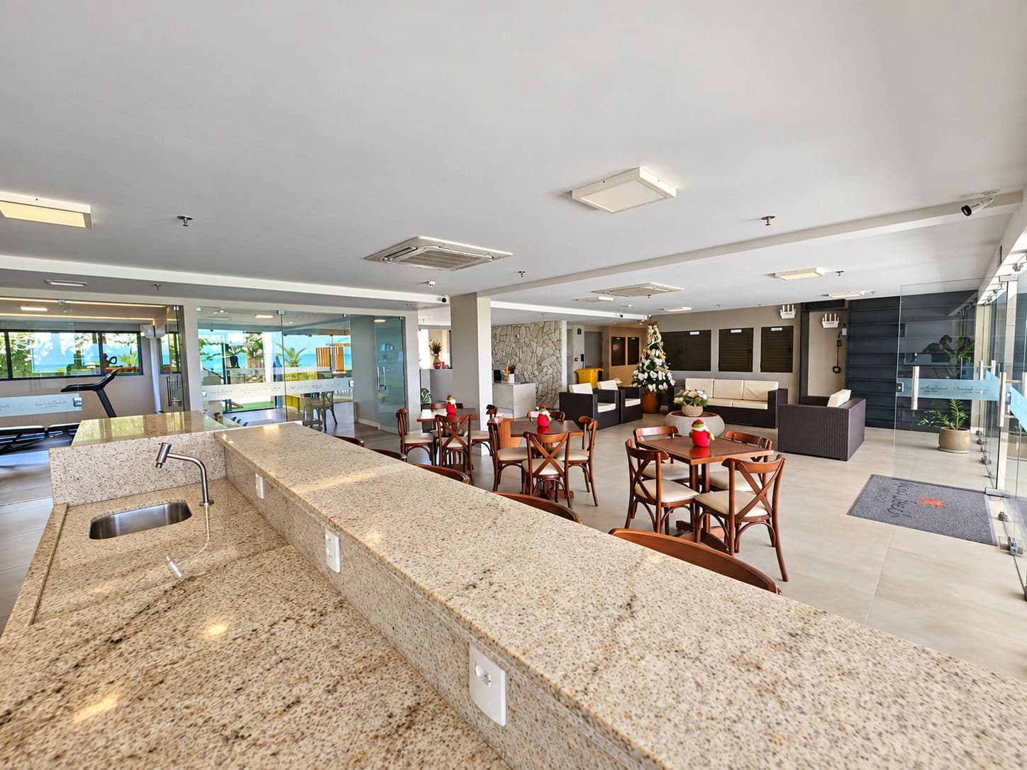 Bancada do coffee shop do Kauai Beach Residence, com o hall e o espaço fitness ao fundo