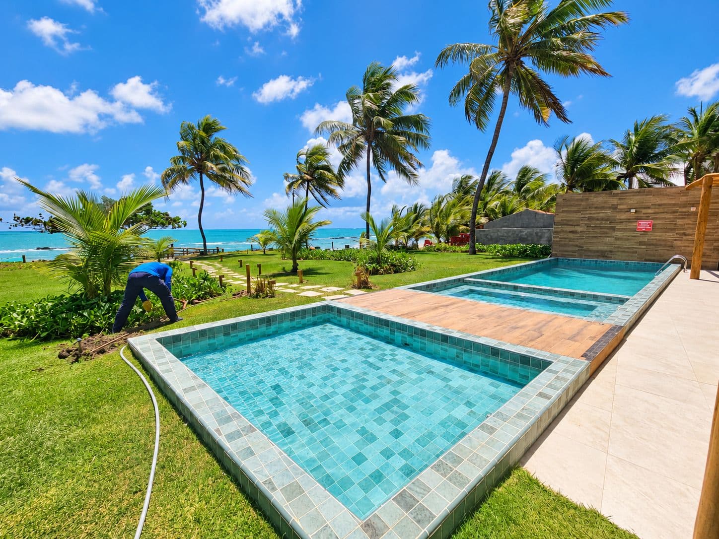 Piscinas do Kauai Beach Residence com jardim e o mar de Tamandaré ao fundo